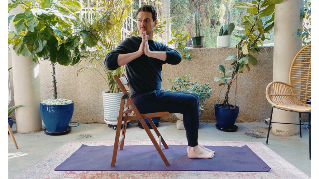 Man sitting on a chair on his yoga mat with his upper body twisting to the right in Half Lord of the Fishes