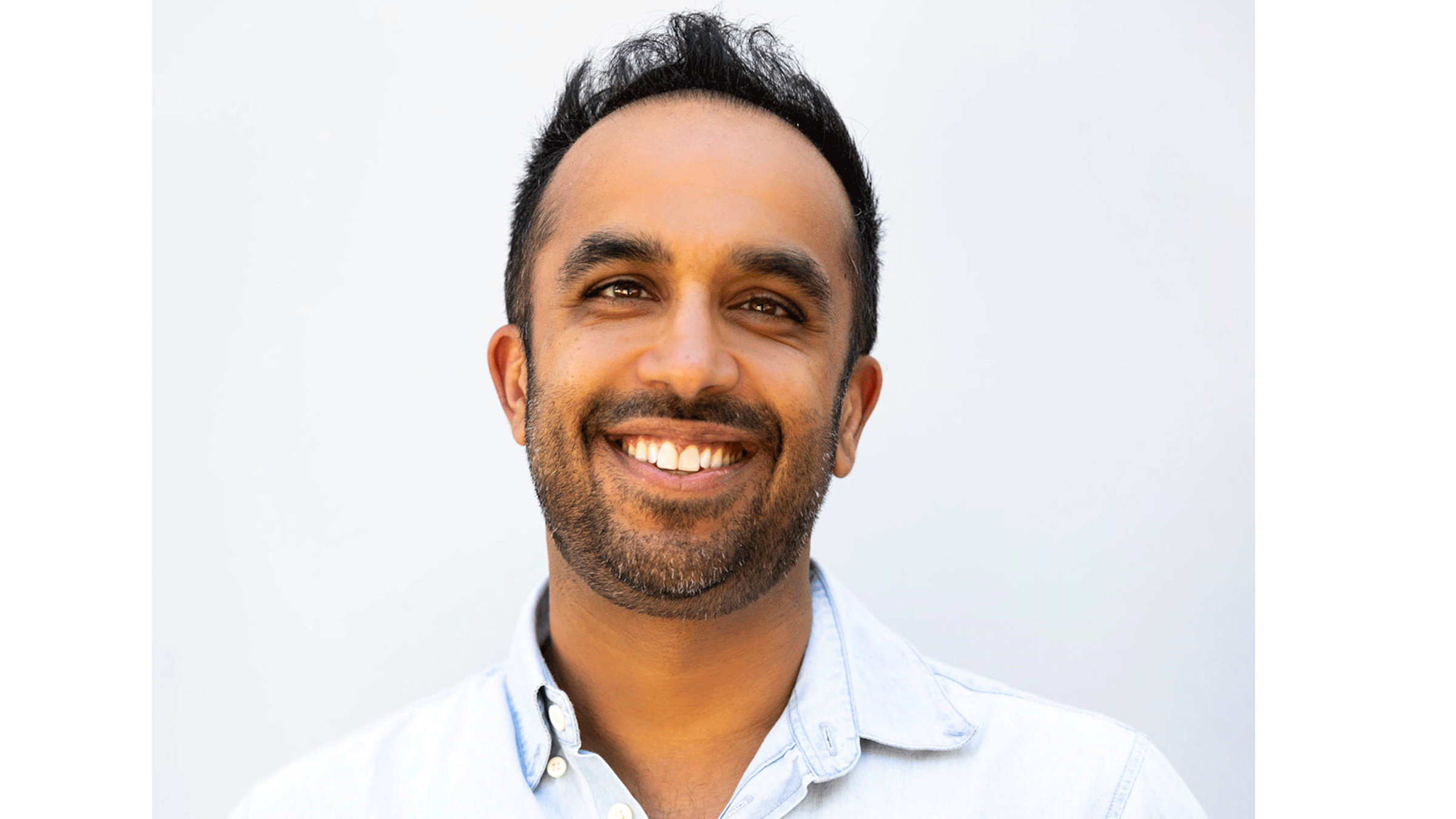 Neil Pasricha standing and grinning looking at the camera