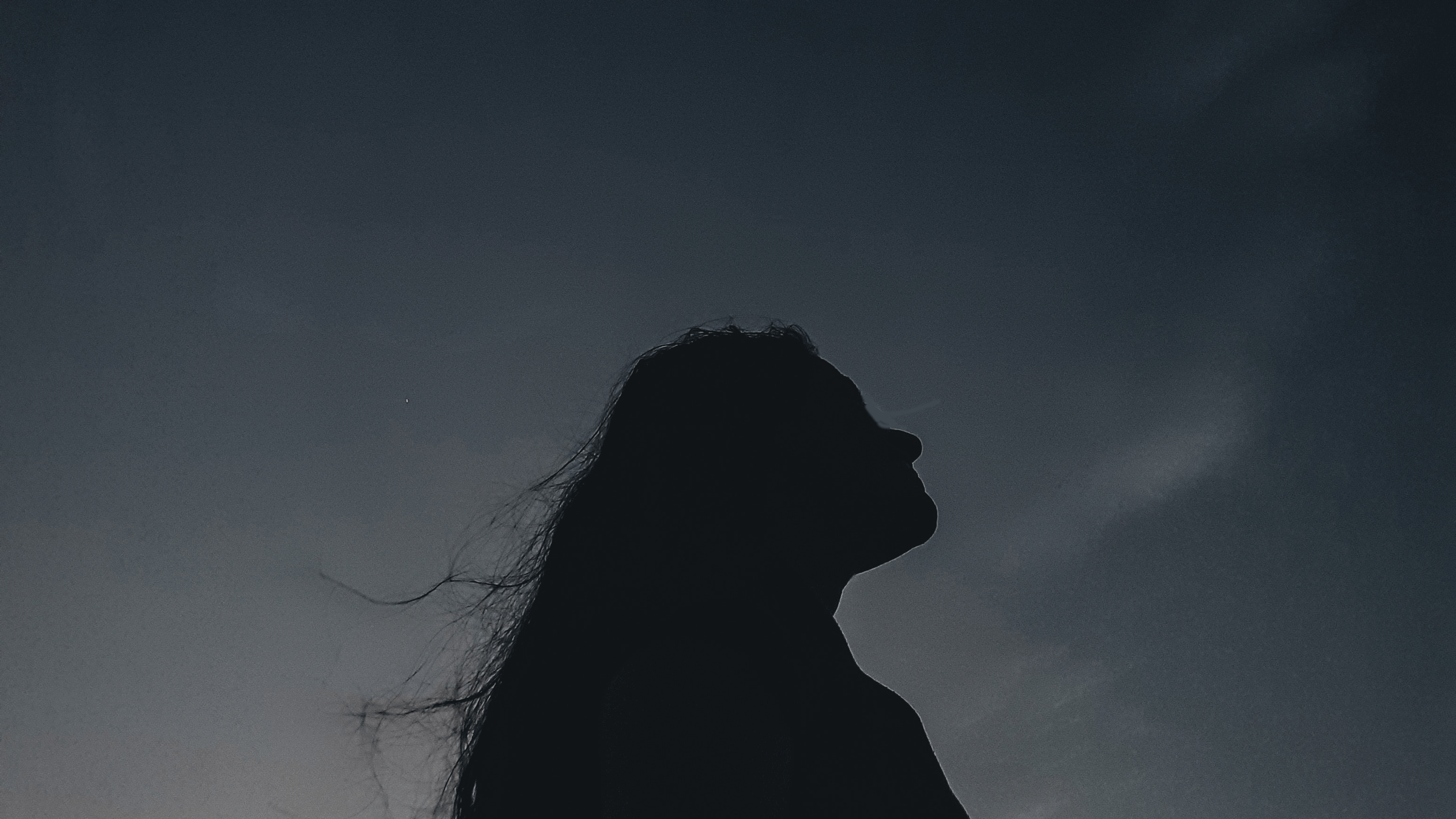 A woman standing outside at night gazing at the stars and thinking about the astrology of the week