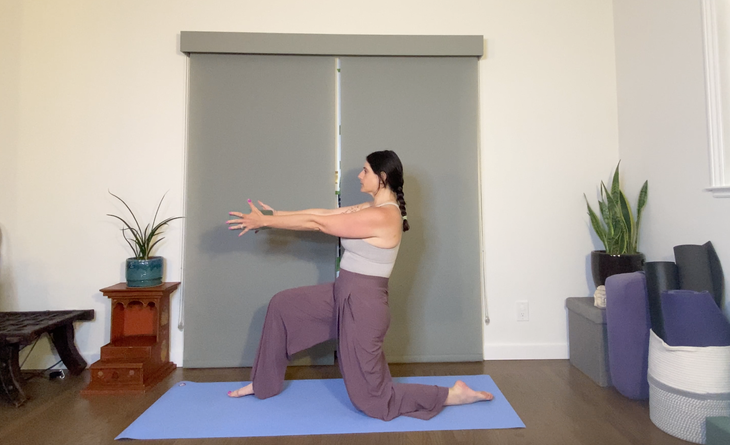 Dark haired woman in purple pants kneels on yoga mat doing a low lunge while holding a yoga block in front of her
