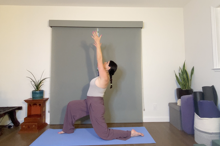 Woman in purple pants practices Low Lunge with arms extended