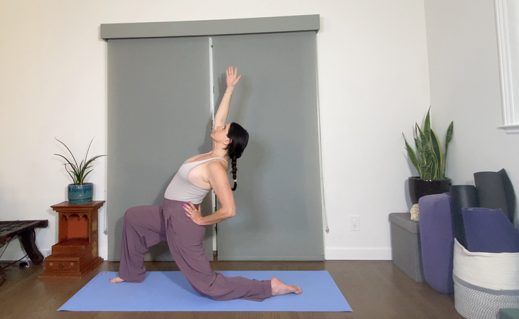 Woman in purple pants practices Ustrasana, Camel Pose variation