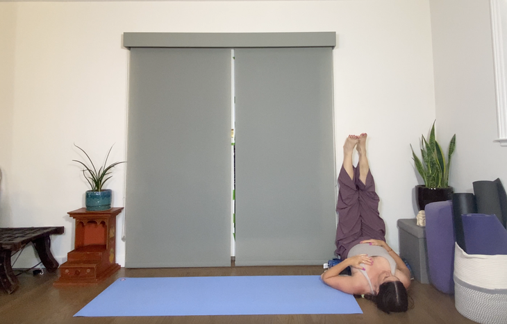 Woman practices Viparita Karani, Legs Up the Wall