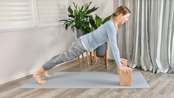 Woman practicing plank pose with hands on blocks