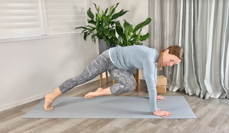 Woman practicing crunches in Plank Pose on a yoga mat