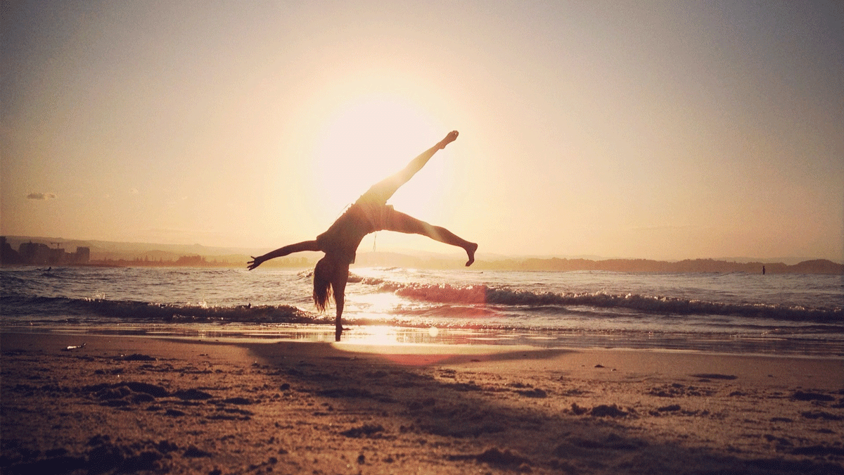 Woman on a beach practicing cartwheels while contemplating the weekly astrology forecast