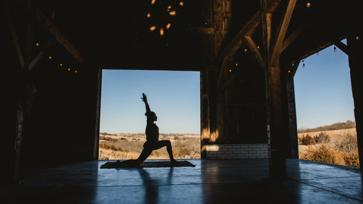 A woman practices yoga on a yoga mat in a restored Iowa barn at a yoga retreat