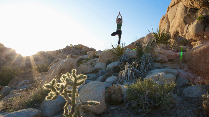 A woman practices yoga on a rock in Joshua Tree Park