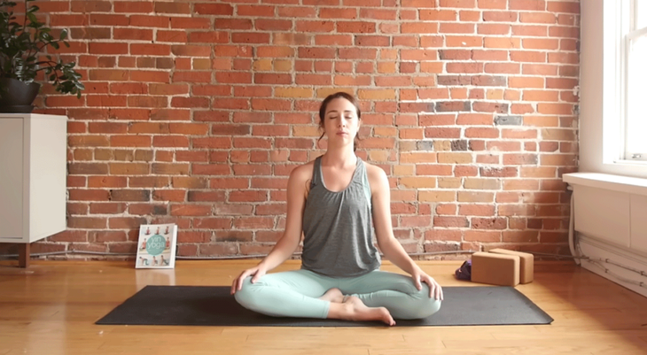 Cassandra Reinhardt practices a comfortable sitting position with her eyes closed at the end of a 10-minute morning yoga session.