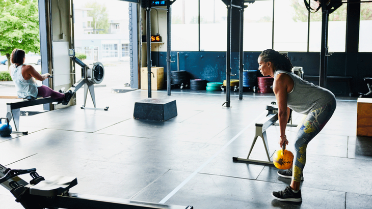 A gym with row machine and kettlebells and women working out