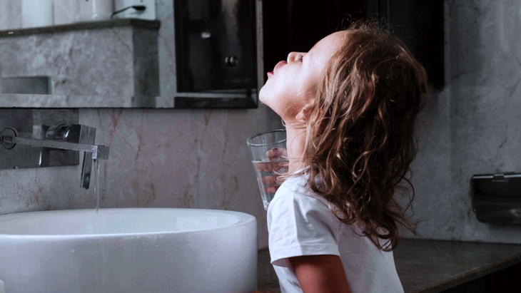 The child gargles while standing near the mirror