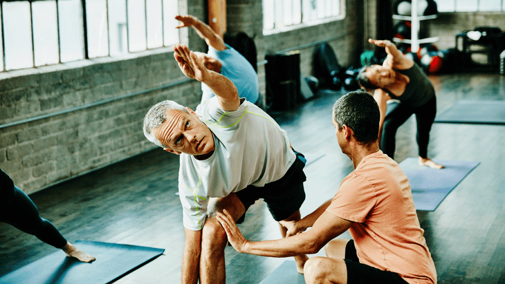 Yoga teacher adjusting student in Extended Side Angle