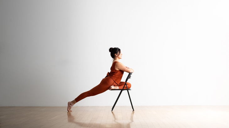 Noemi Nunes practices pigeon pose in a chair.