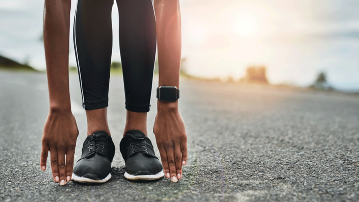 Woman runner leaning forward stretching