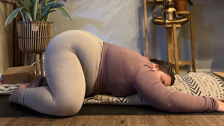 Woman practicing the yin yoga version of Child's Pose on a yoga mat
