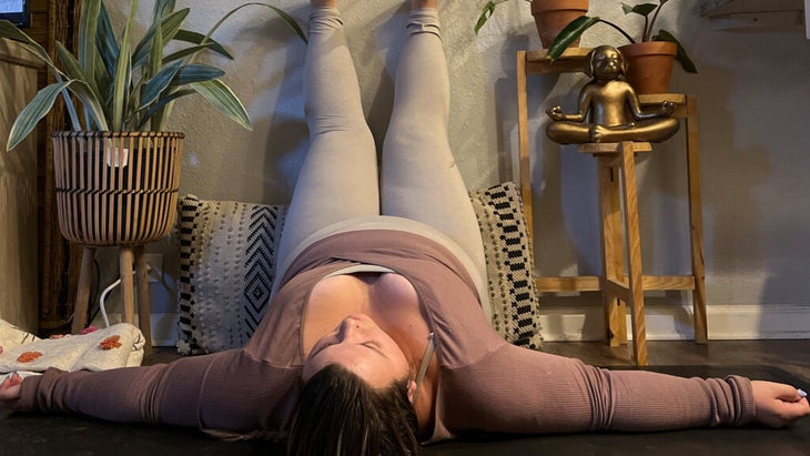 Woman lying on her back on a yoga mat with her legs up the wall