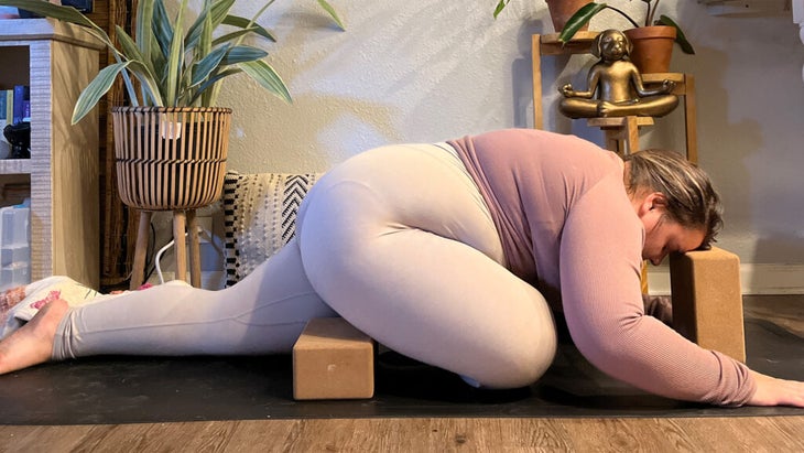 Woman practicing Sleeping Swan, the yin version of Pigeon Pose, on her yoga mat