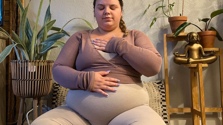 Woman sitting on a yoga mat practicing deep, slow breathing for emotional calming and support