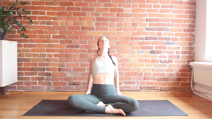 Yoga with Kassandra sitting on a yoga mat practicing 10-minute evening yoga shoulder shrugs