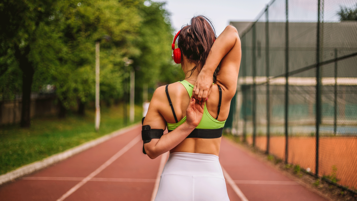 Woman runner practicing some shoulder stretches for athletes