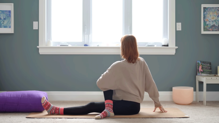 Yoga with Kassandra in a seated twist on her yoga mat