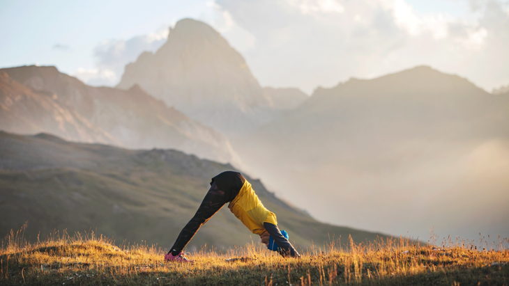 Hiker in the mountains stretching in Downward-Facing Dog