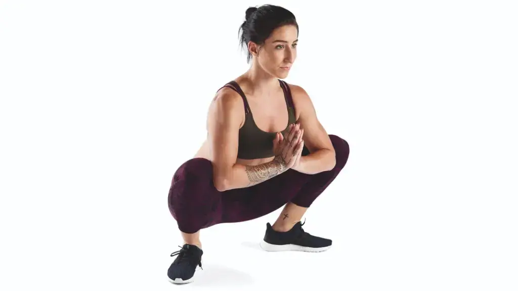 Woman athlete practicing prayer squat, or Malasana, to strengthen her hips and support her knees