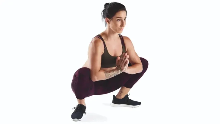 Woman athlete practicing prayer squat, or Malasana, to strengthen her hips and support her knees