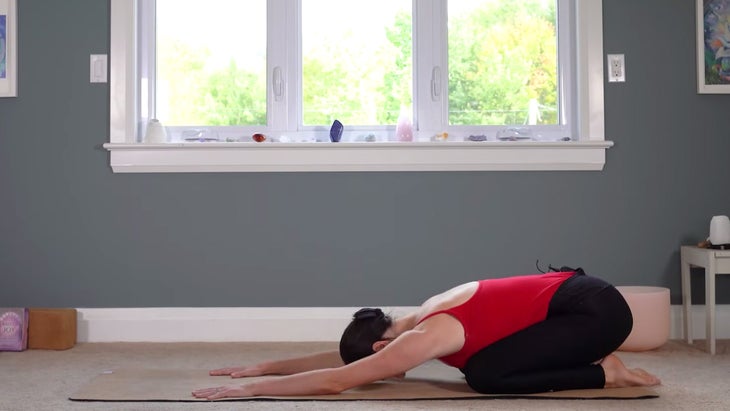 Woman on a yoga mat practicing Child's Pose