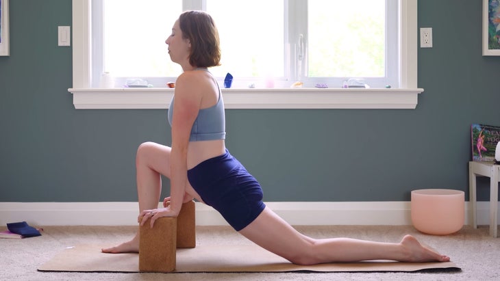 female yoga instructor in dragon pose, modified with blocks.