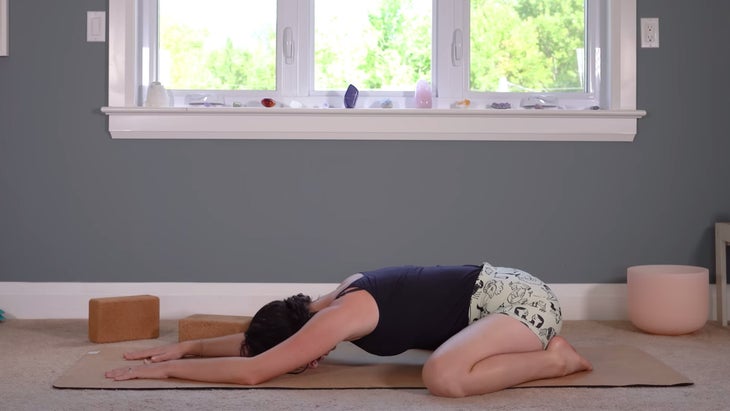Woman lying on a yoga mat practicing Child's Pose