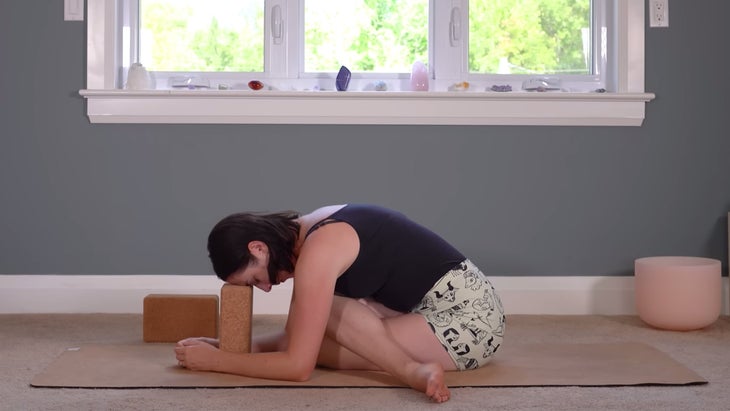 Woman sitting cross-legged on the floor practicing yin yoga for Scorpio