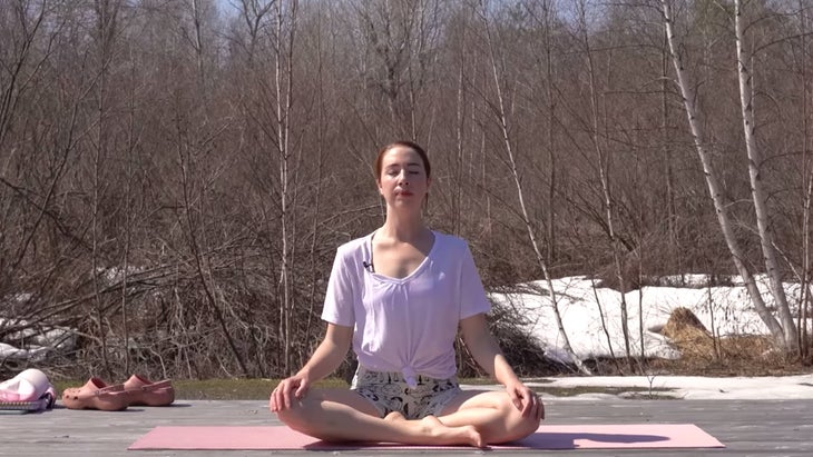 Woman in seated meditation pose outside on a yoga mat