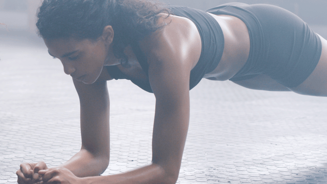 Woman practicing forearm plank while doing a 10-minute workout at home