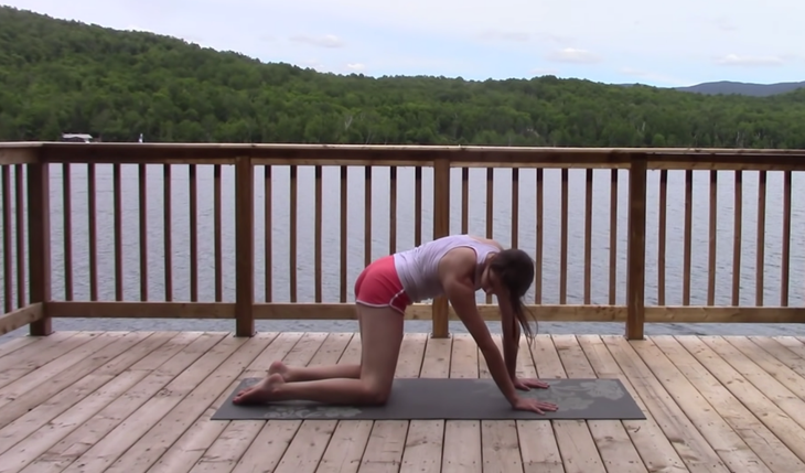 Yoga With Kassandra doing Cat Cow with a side stretch outside on a mat during a 20 minute yoga class