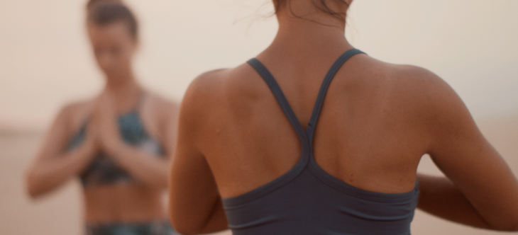 Two women practicing ashtanga yoga while sitting in Sukhasana