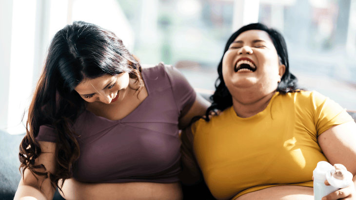 Two yoga students laughing out loud while sitting around after class