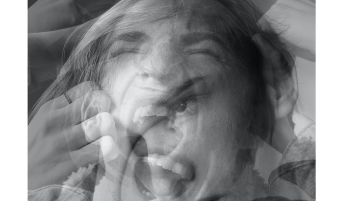 Black-and-white photo of a woman struggling to meditate with her hands on her head and all her thoughts distracting her.