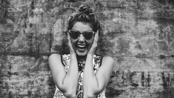 Woman wearing sunglasses laughing because she's overcome common obstacles to meditation.