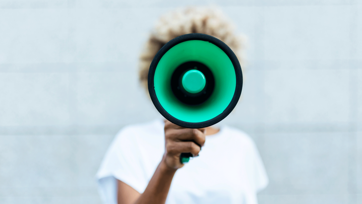 Woman with bleached hair holding a megaphone in front of her to represent finding your voice