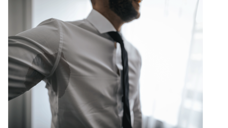 Man wearing a white dress shirt and tie with sweat marks on his armpits from psychological stress