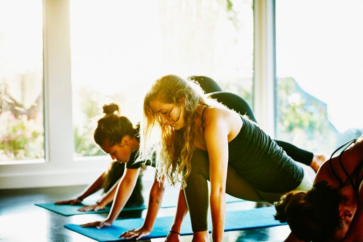 Students in a yoga class transition from Down Dog to Low Lunge while teaching a yoga teacher tip about noticing when they are tired.