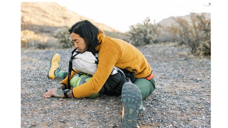 Backpacker leaning forward onto his pack as a stretch 