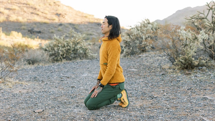 Backpacker practicing yoga near his tent along a desert trail in Arizona