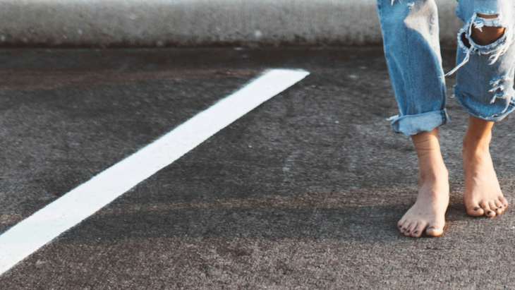 A woman walks barefoot in a parking lot after a yoga class.