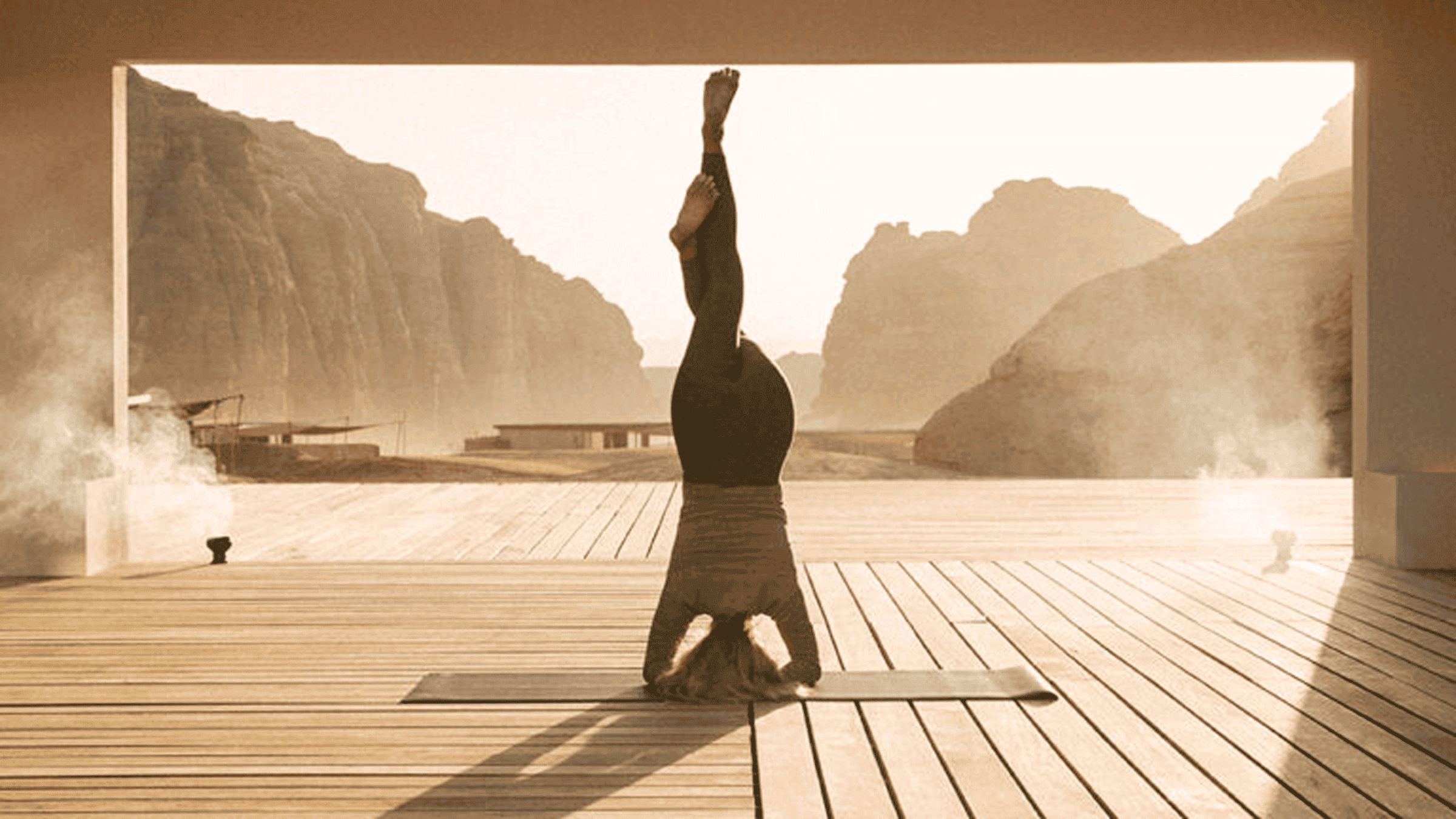 Person doing yoga headstand with mountain views in the background.