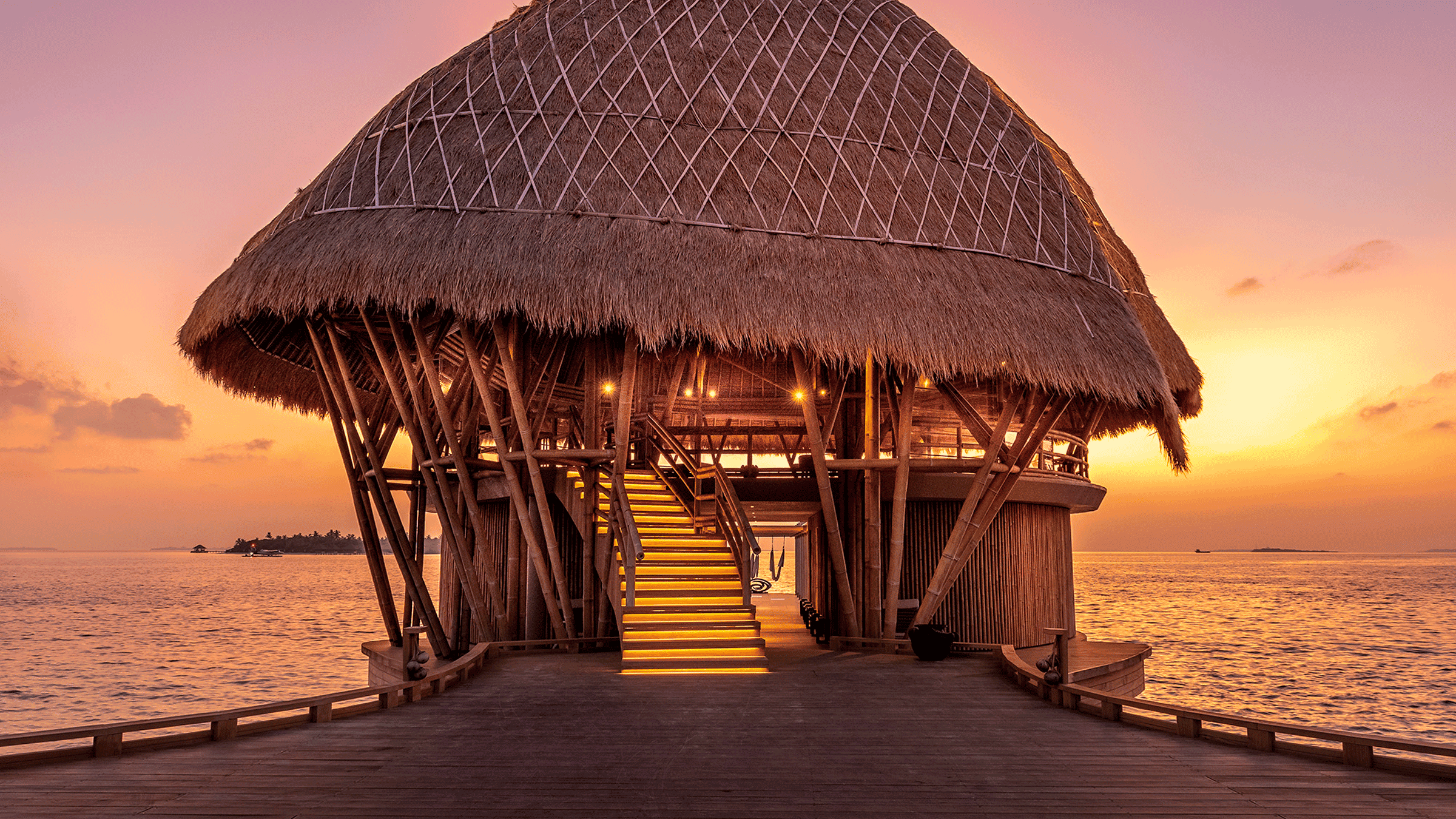 Beach hut with a sun setting over the ocean.