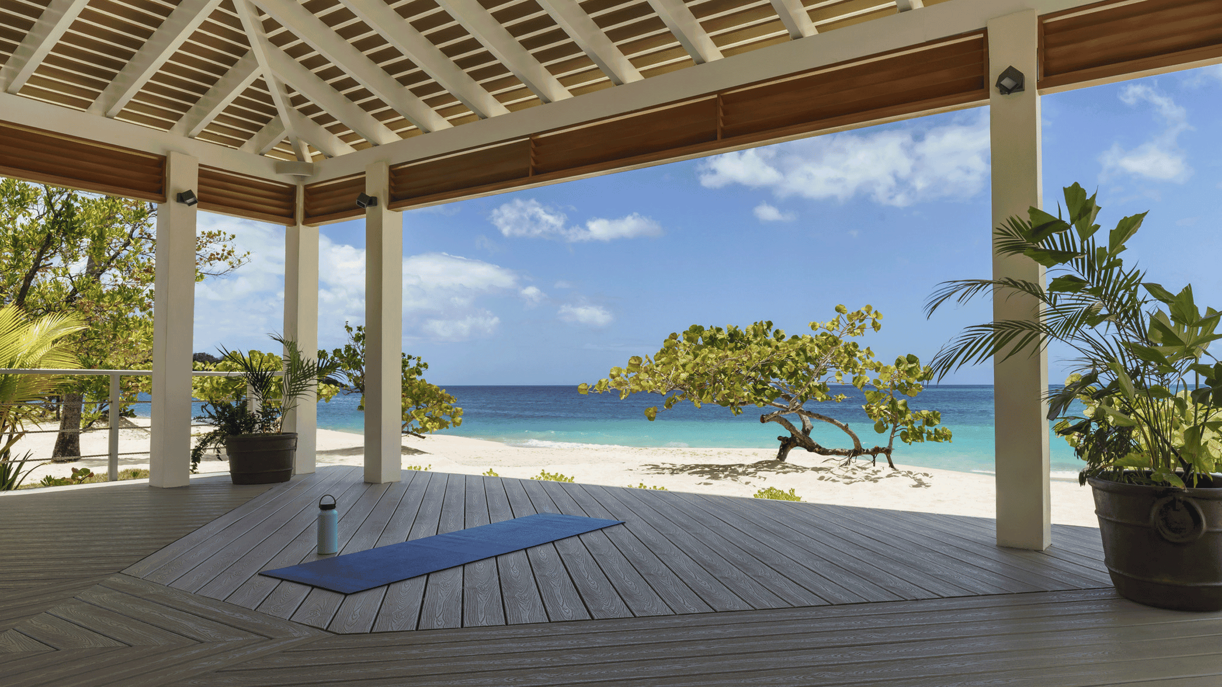Beach hut overlooking sea, sand, and lush greenery.