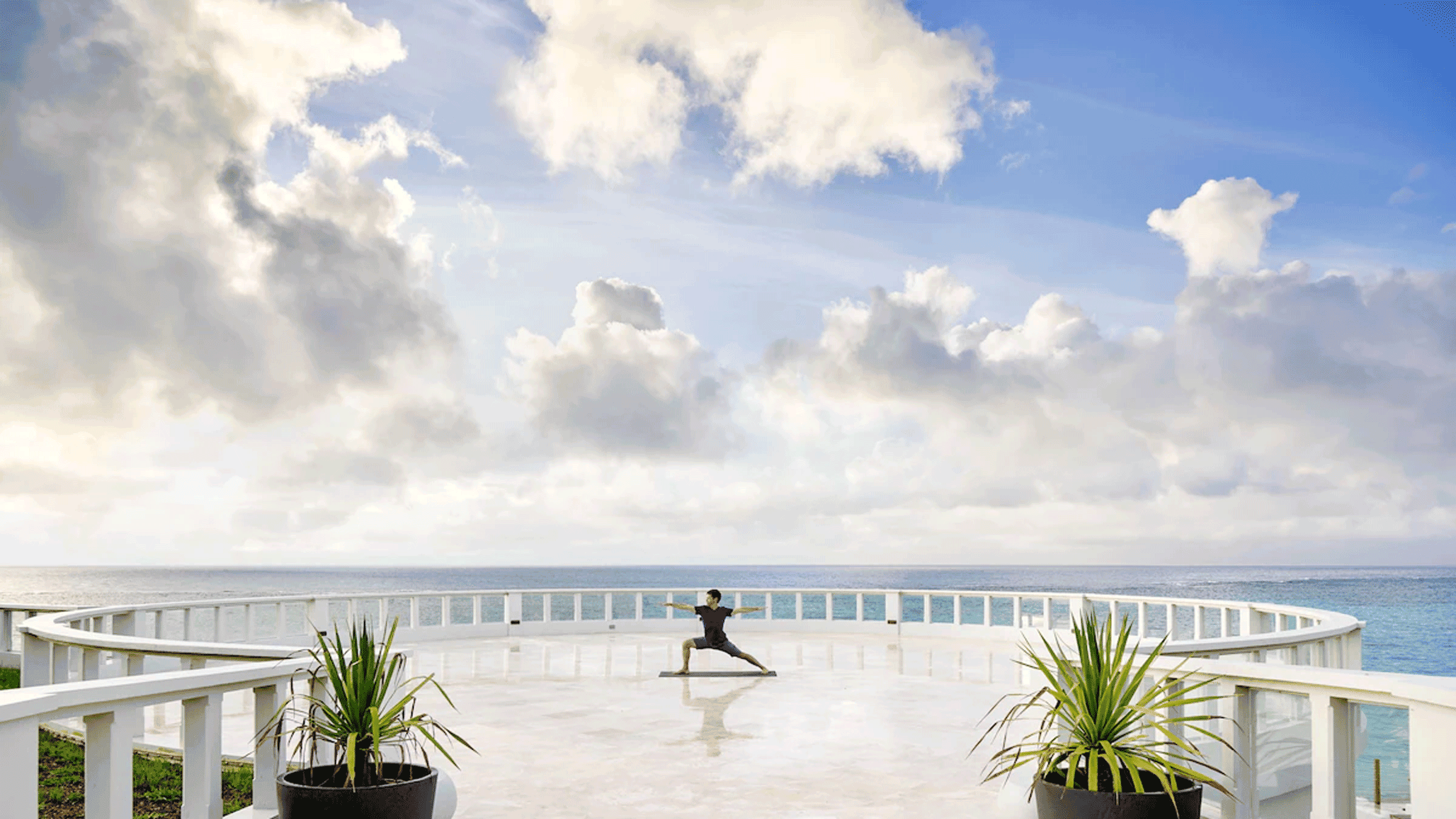 Person practicing yoga on a platform that extends into the caribbean