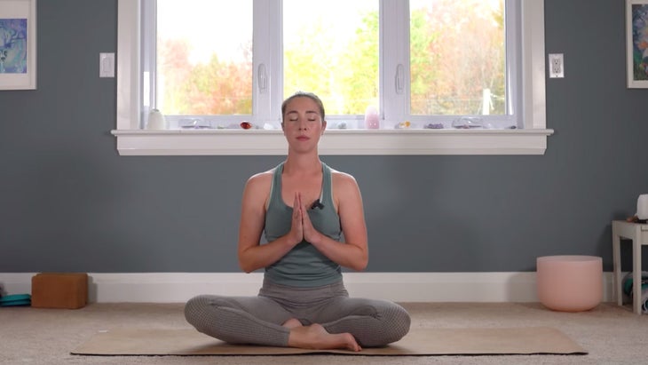 Woman sitting on a yoga mat meditating after practicing yoga for Capricorn